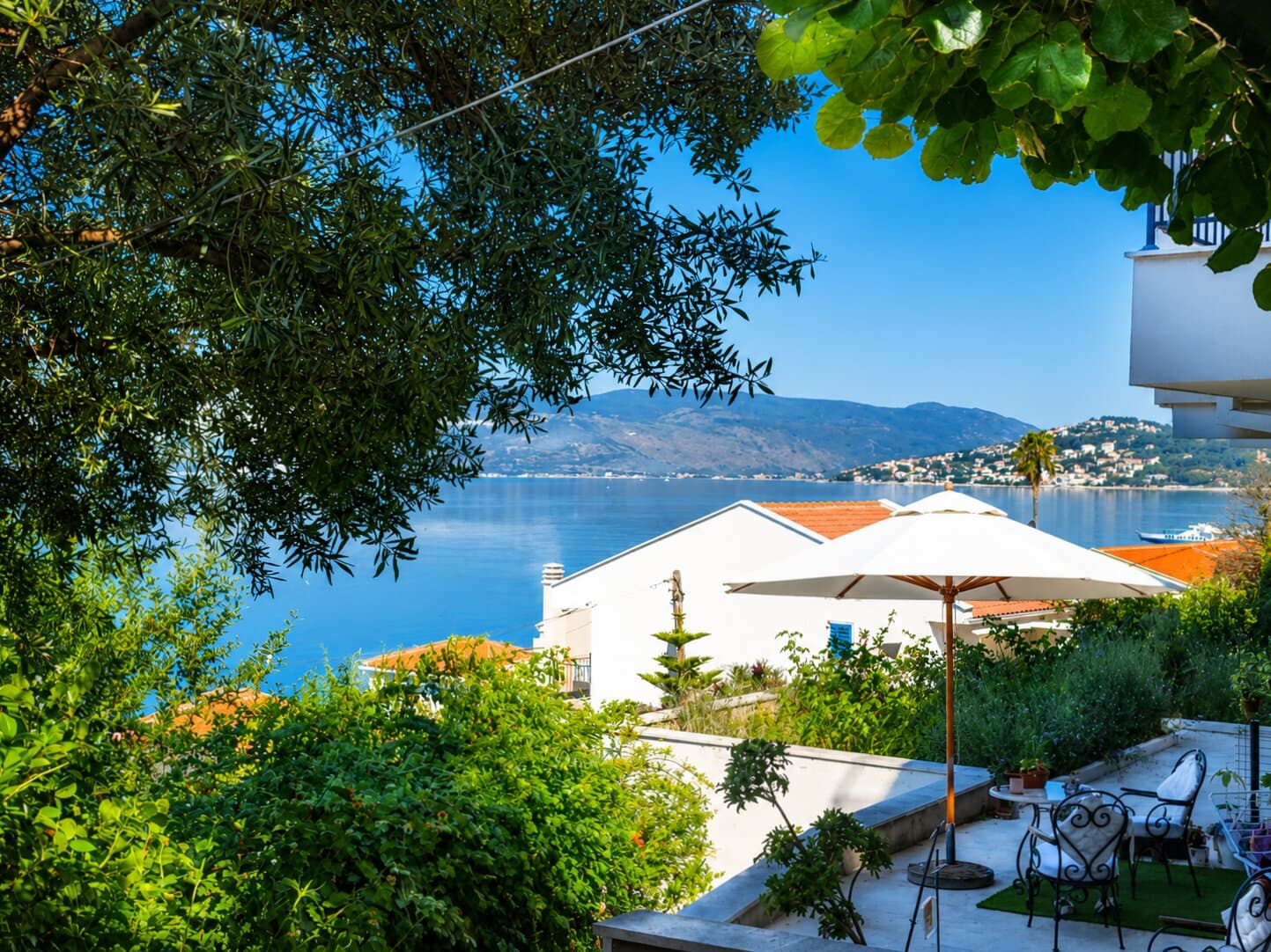 The villa terrace with its white umbrella above the rooftops and the bay